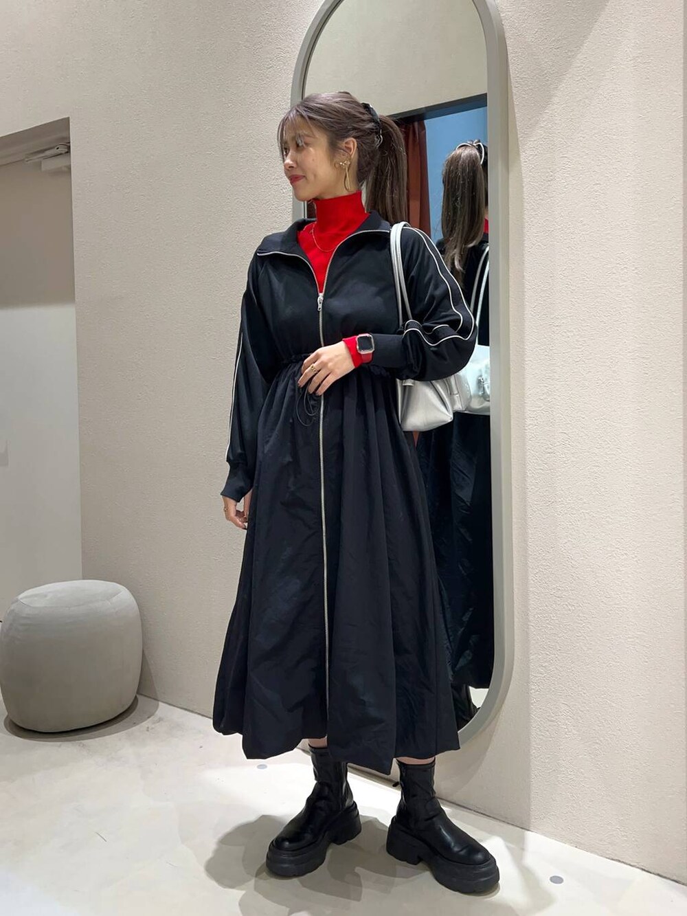 レッド系のニット/セーター、シルバー系のショルダーバッグ、ブラック系のワンピースを着用したレディースの冬コーディネートの2枚目の写真