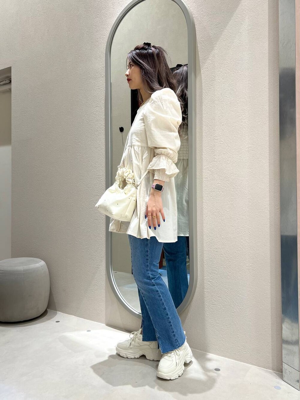 ベージュ系のハンドバッグ、ホワイト系のスニーカー、ベージュ系のTシャツ/カットソーを着用したレディースの冬コーディネートの2枚目の写真