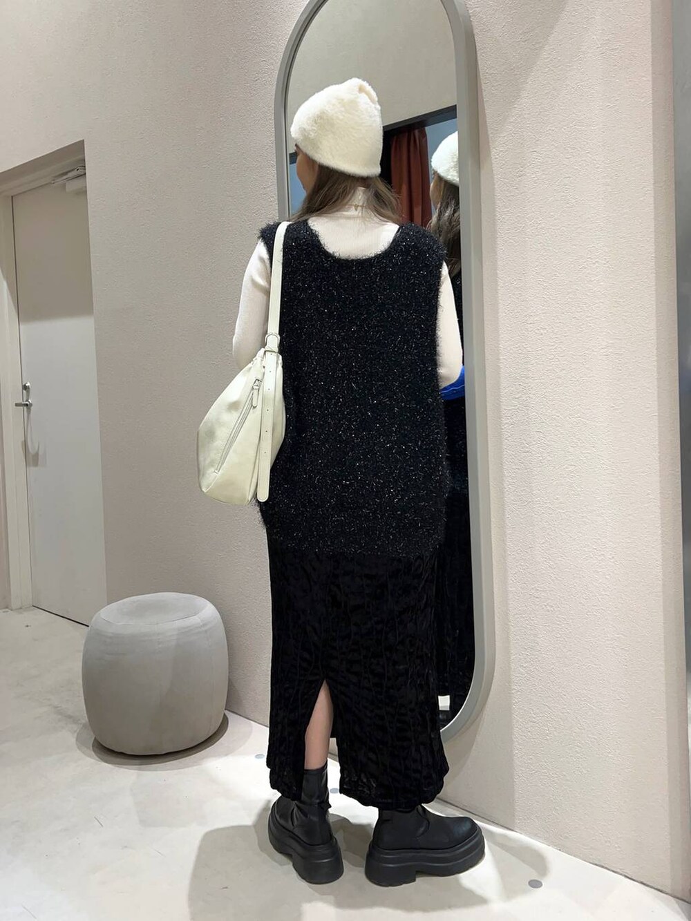 ブラック系のワンピース、ホワイト系のショルダーバッグ、ホワイト系のニット/セーターを着用したレディースの冬コーディネートの4枚目の写真