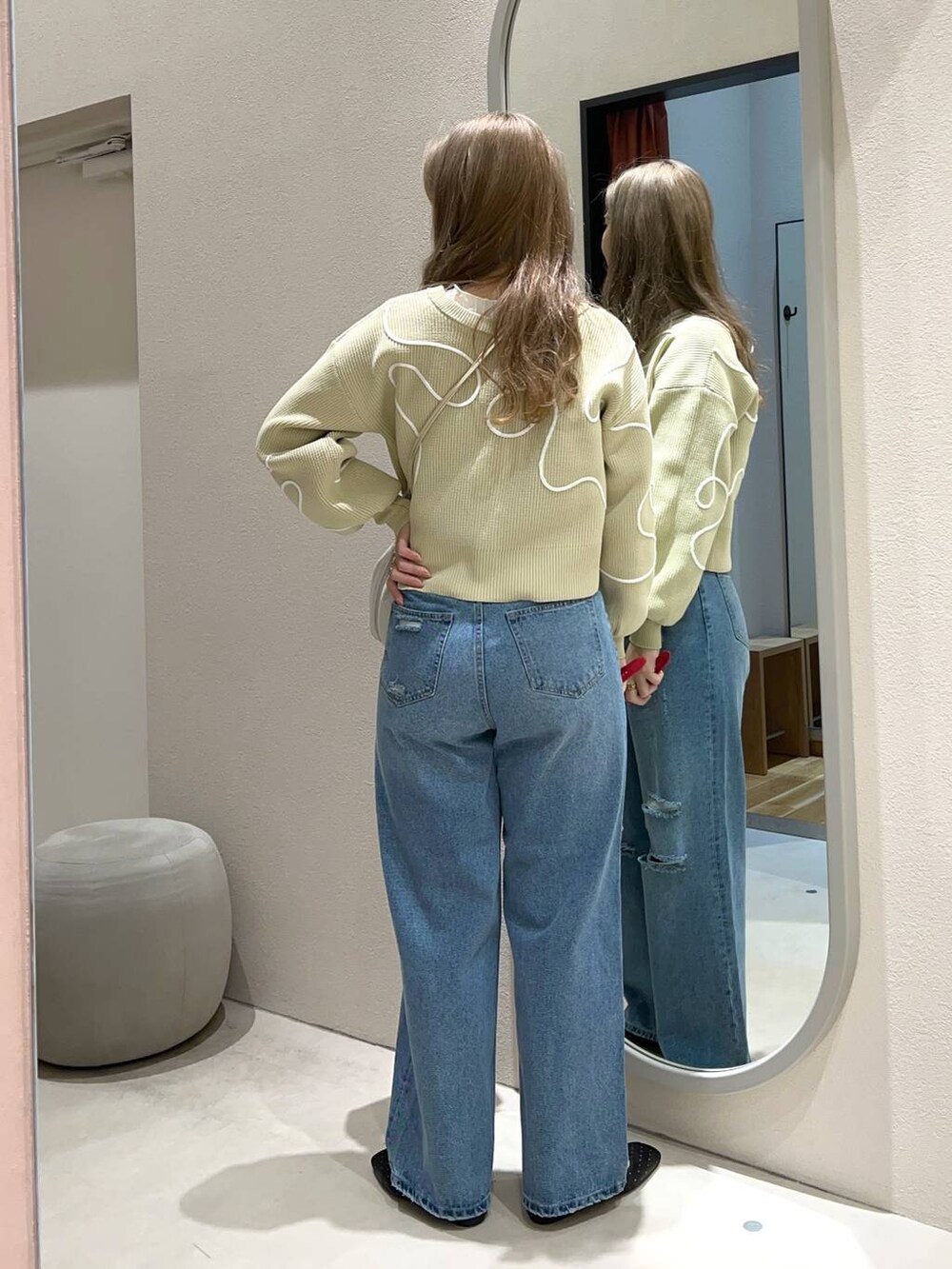 ベージュ系のTシャツ/カットソー、ブルー系のデニムパンツ、ホワイト系のショルダーバッグを着用したレディースの冬コーディネートの3枚目の写真