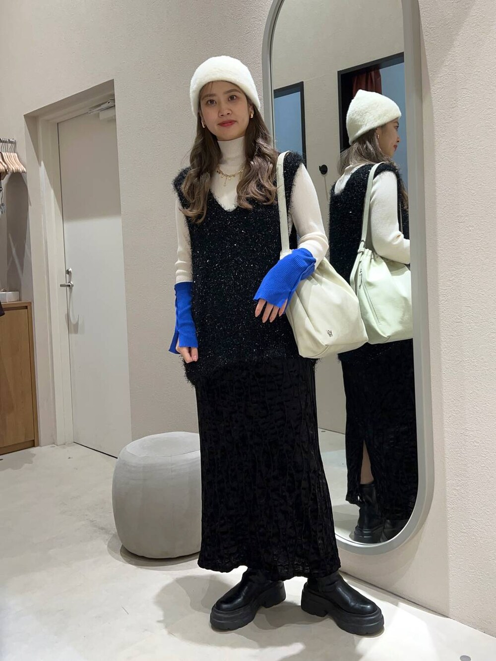 ブラック系のワンピース、ホワイト系のショルダーバッグ、ホワイト系のニット/セーターを着用したレディースの冬コーディネートの2枚目の写真