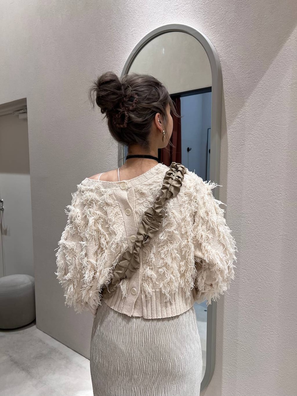 ホワイト系のスカート、ホワイト系のカーディガン/ボレロ、ベージュ系のスマホグッズを着用したレディースの冬コーディネートの4枚目の写真