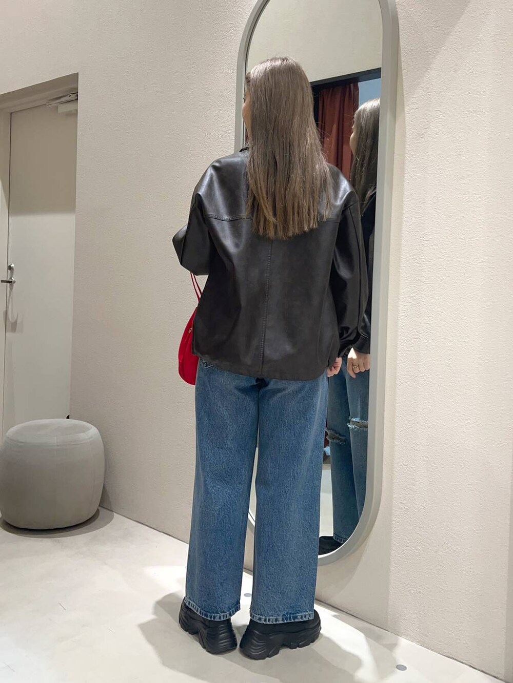 レッド系のハンドバッグ、ベージュ系のスニーカー、ブルー系のデニムパンツを着用したレディースの冬コーディネートの3枚目の写真