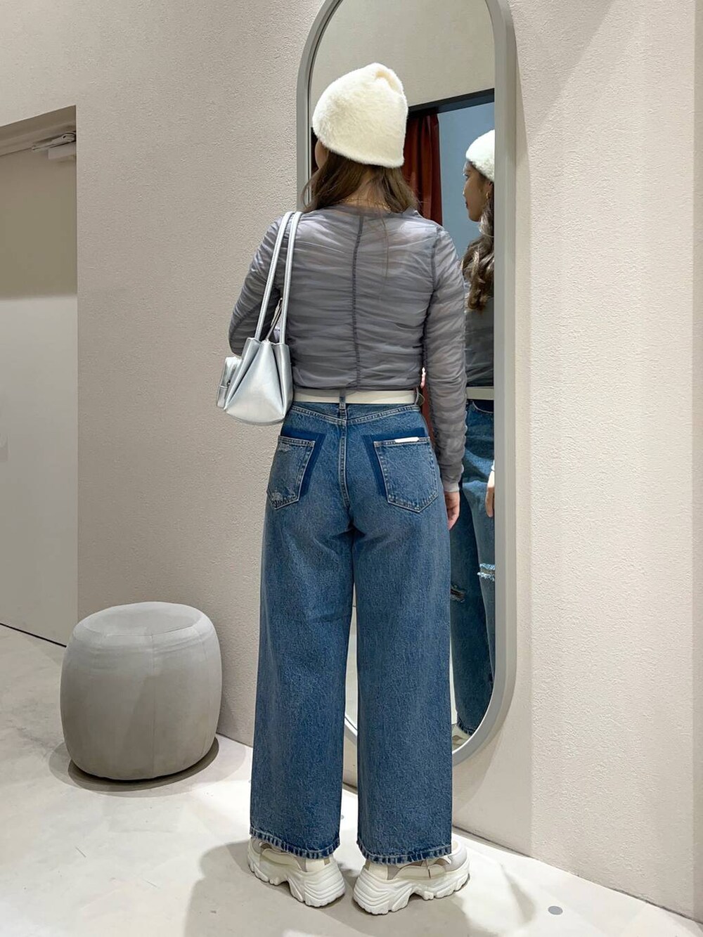 シルバー系のショルダーバッグ、ベージュ系のスニーカー、ブルー系のデニムパンツを着用したレディースの冬コーディネートの3枚目の写真