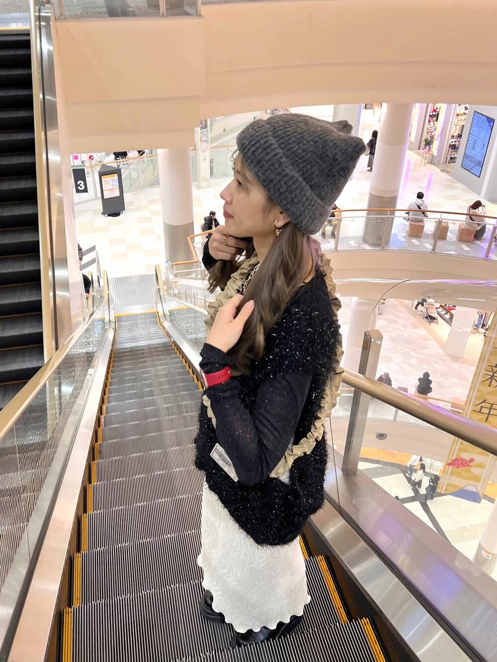 ホワイト系のスカート、ブラック系のニット/セーター、ブラック系のTシャツ/カットソーを着用したレディースの冬コーディネートの4枚目の写真