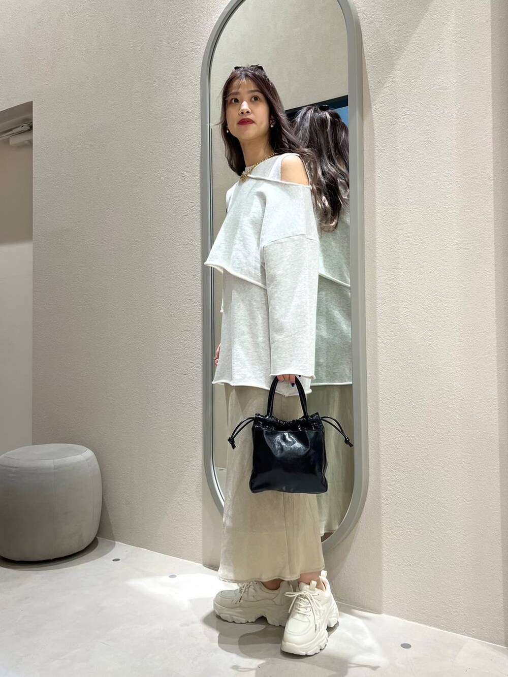 グリーン系のスカート、ホワイト系のスニーカー、ブラック系のハンドバッグを着用したレディースの冬コーディネートの2枚目の写真