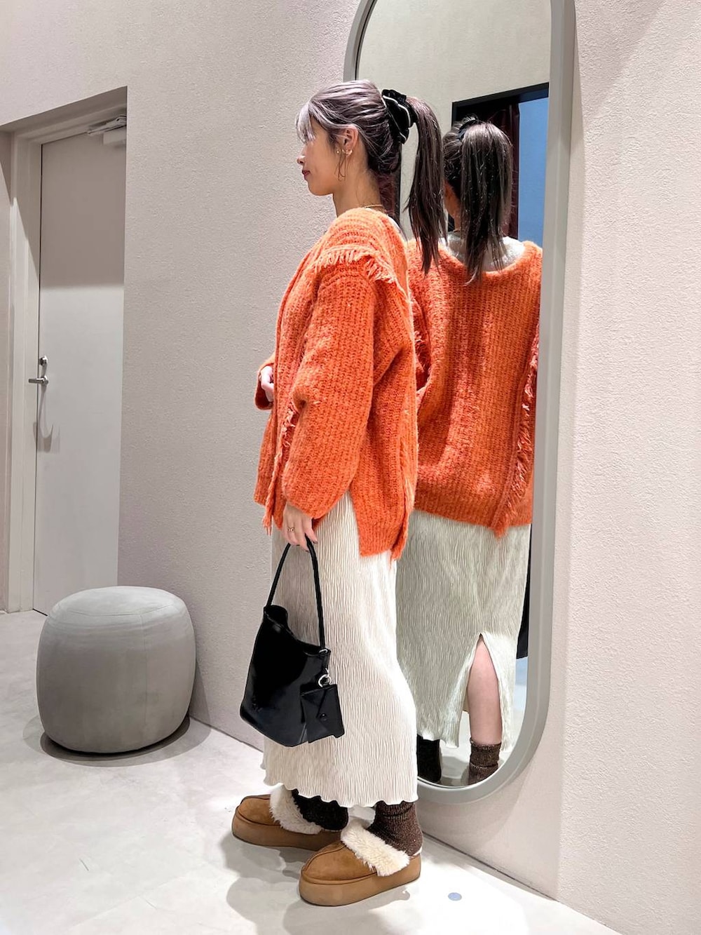 オレンジ系のニット/セーター、ホワイト系のスカート、ホワイト系のTシャツ/カットソーを着用したレディースの冬コーディネートの2枚目の写真