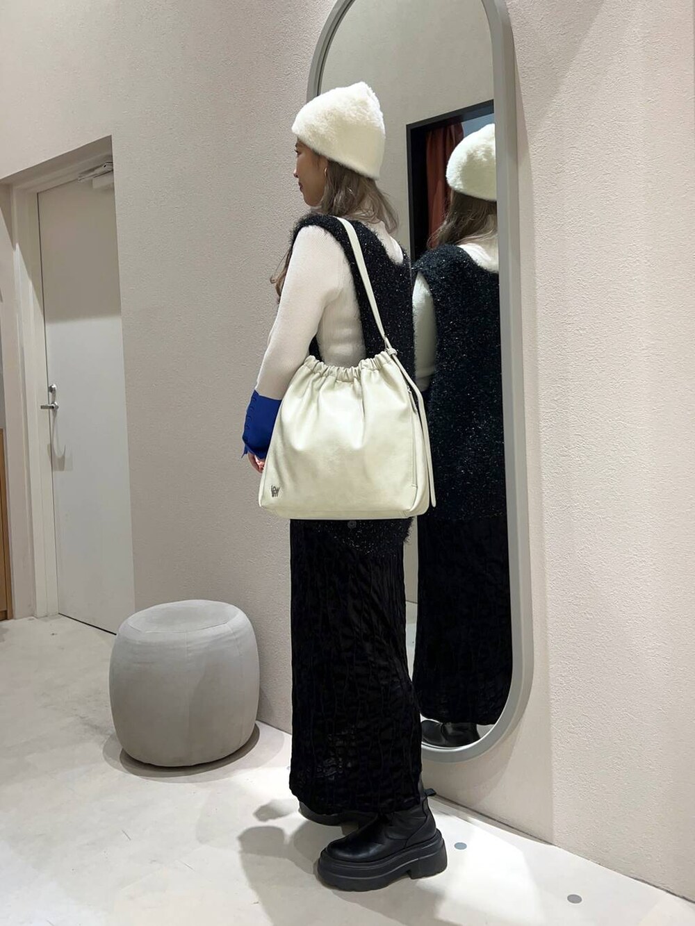 ブラック系のワンピース、ホワイト系のショルダーバッグ、ホワイト系のニット/セーターを着用したレディースの冬コーディネートの3枚目の写真