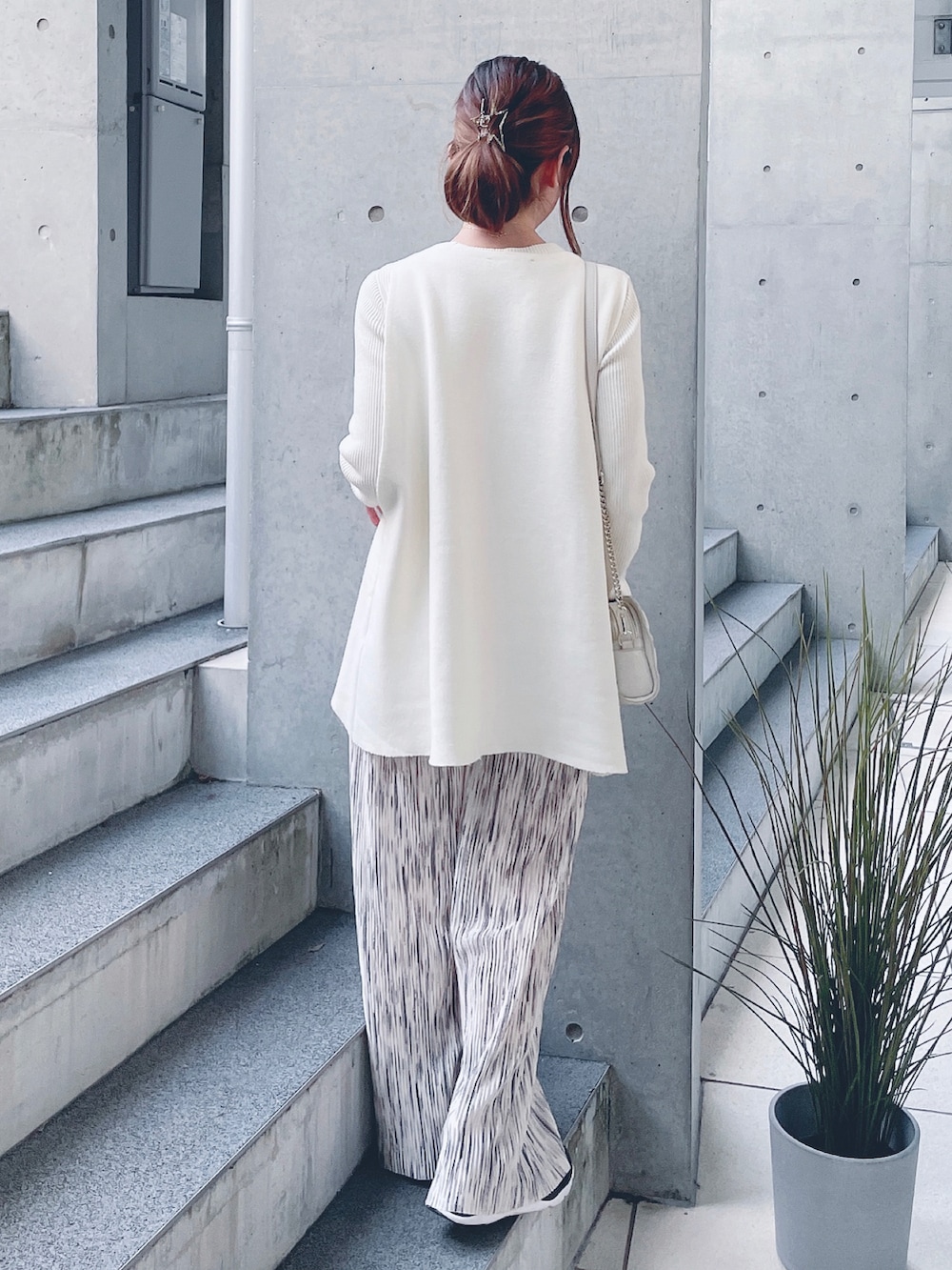 ホワイト系のベスト、ベージュ系のその他パンツ、ゴールド系のショルダーバッグを着用したレディースの秋コーディネートの3枚目の写真