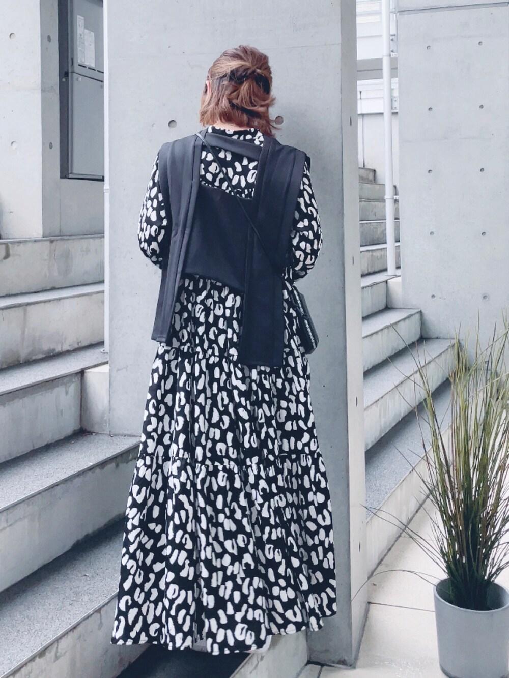 ブラック系のワンピース、ブラック系のベスト、ホワイト系のスニーカーを着用したレディースの春コーディネートの3枚目の写真