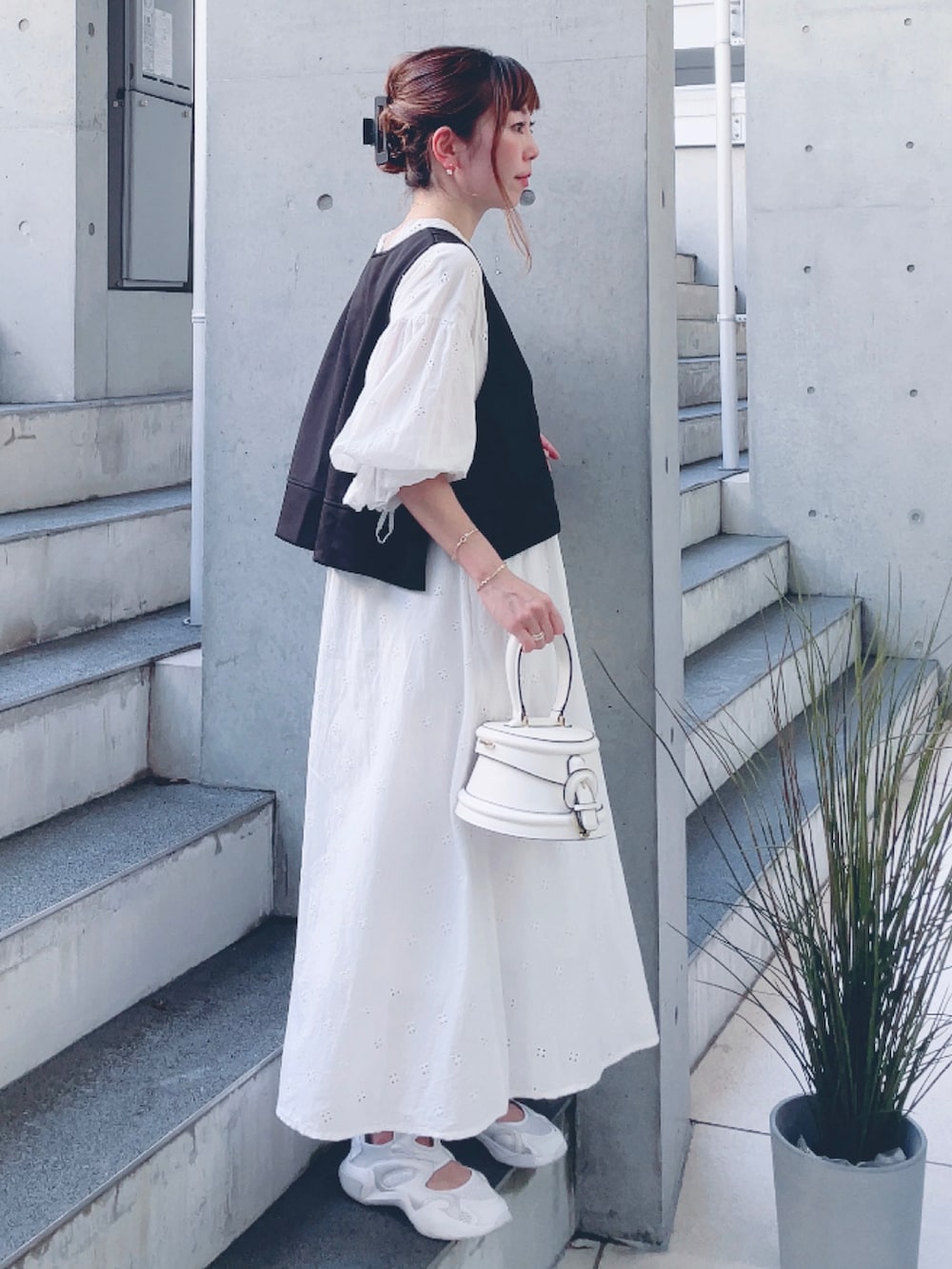 ホワイト系のワンピース、ブラック系のベスト、ホワイト系のスニーカーを着用したレディースの秋コーディネートの3枚目の写真