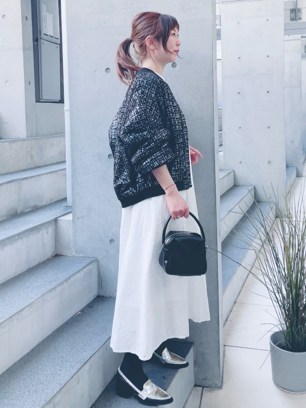ホワイト系のワンピース、ブラック系のブルゾン、ブラック系のハンドバッグを着用したレディースの春コーディネートの2枚目の写真