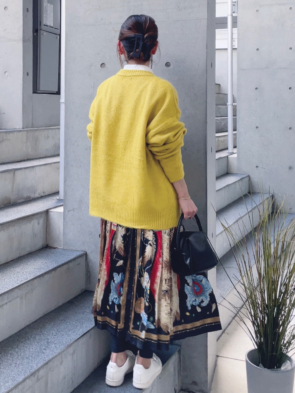 イエロー系のニット/セーター、その他のスカート、ブラック系のハンドバッグを着用したレディースの秋コーディネートの3枚目の写真