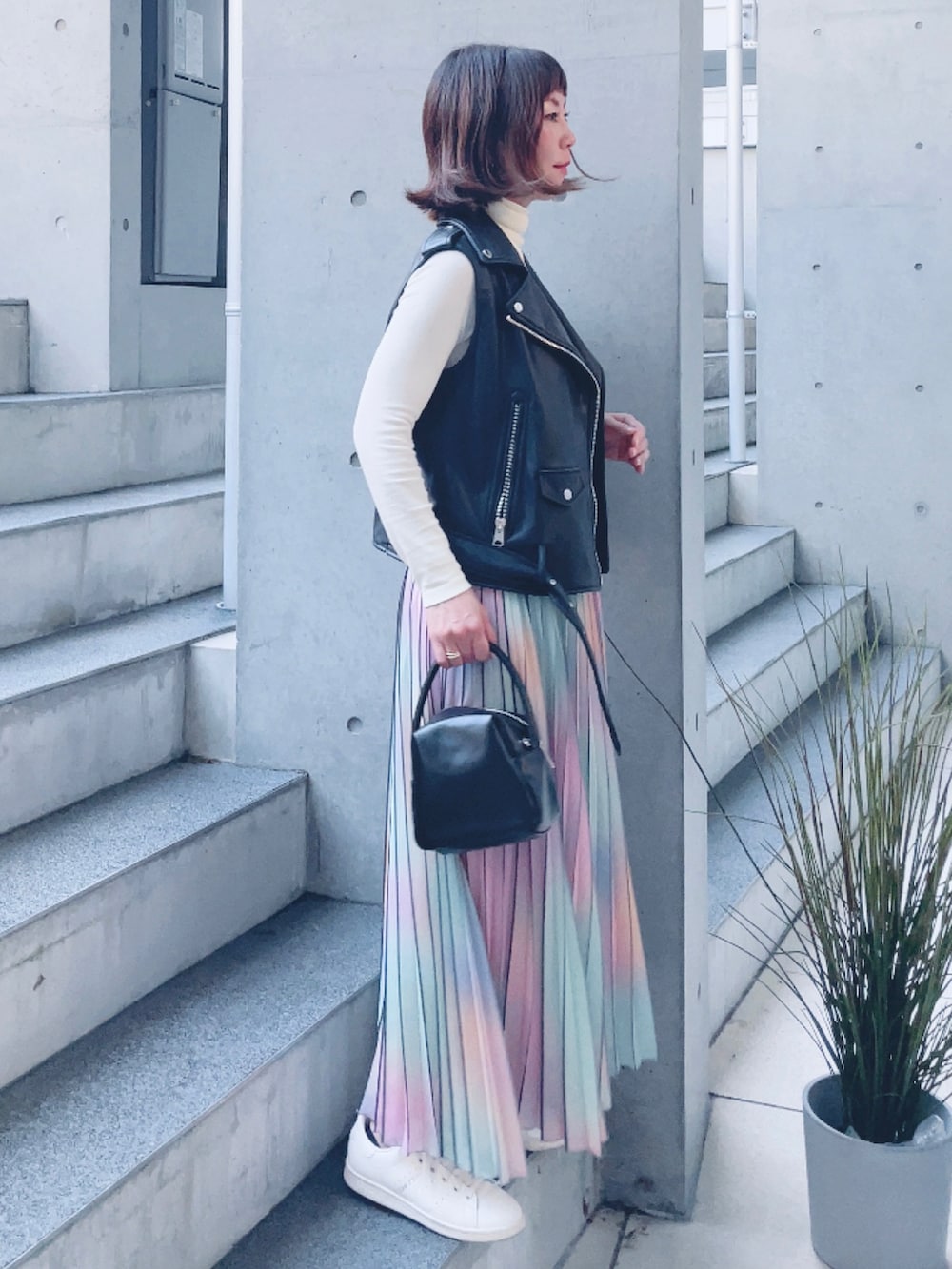 ブラック系のライダースジャケット、ブラック系のハンドバッグ、その他のスカートを着用したレディースの秋コーディネートの2枚目の写真