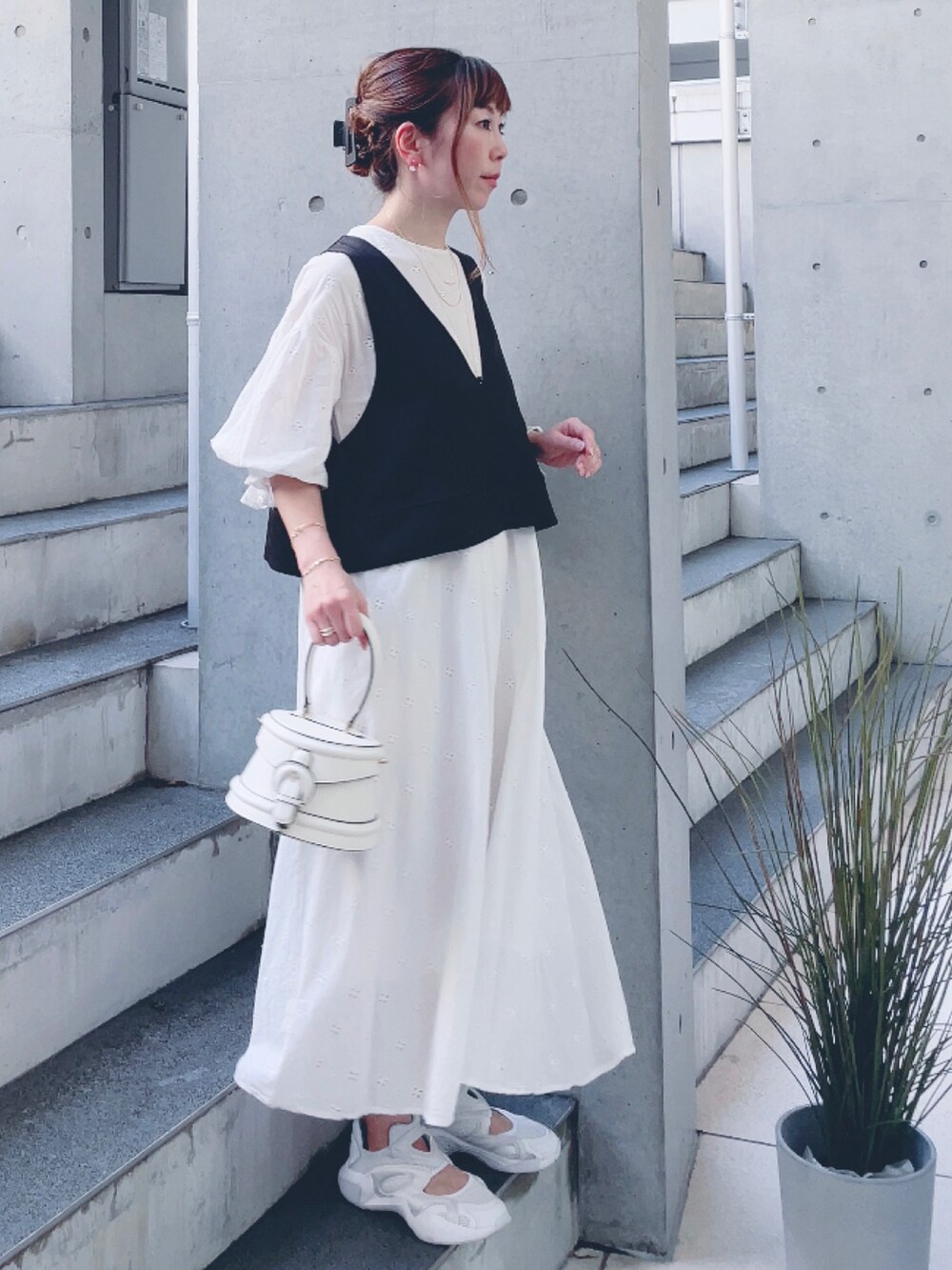 ホワイト系のワンピース、ブラック系のベスト、ホワイト系のスニーカーを着用したレディースの秋コーディネートの2枚目の写真