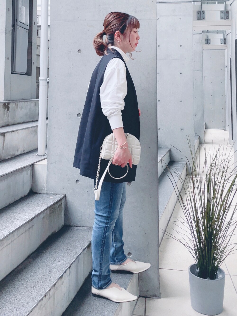 ブルー系のデニムパンツ、ベージュ系のパンプス、ゴールド系のショルダーバッグを着用したレディースの春コーディネートの2枚目の写真