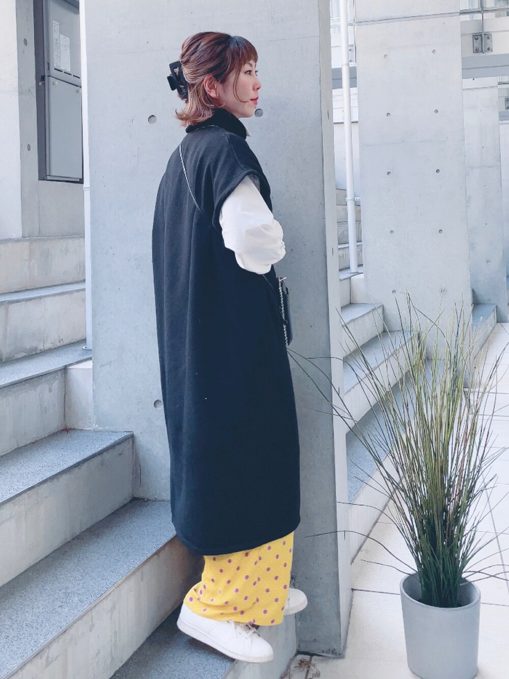 ブラック系のニット/セーター、ホワイト系のシャツ/ブラウス、ベージュ系のスニーカーを着用したレディースの春コーディネートの2枚目の写真