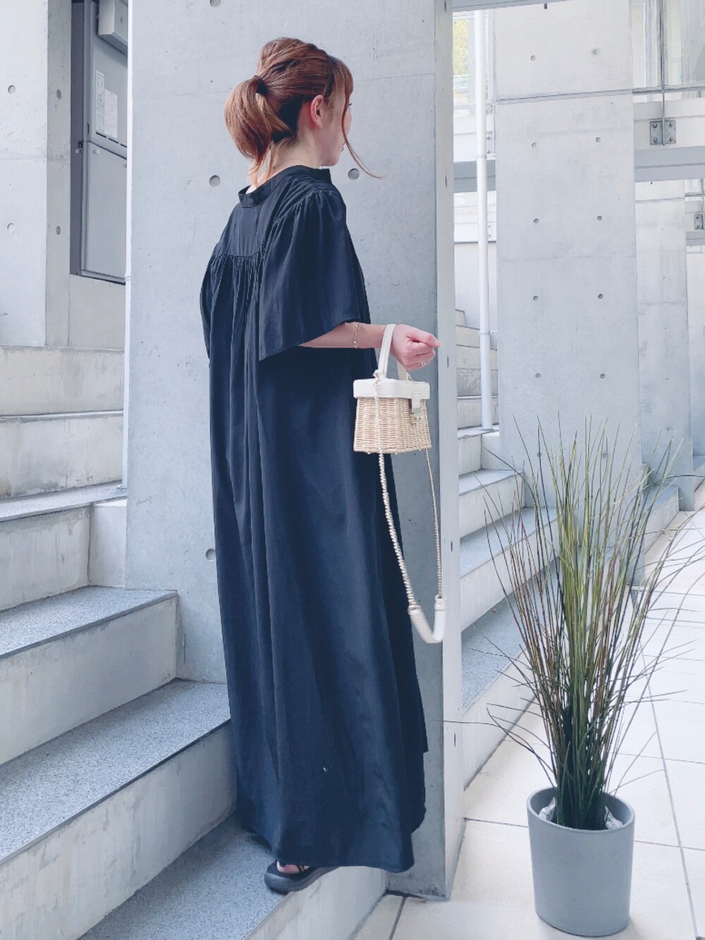 ブラック系のワンピース、ホワイト系のかごバッグ、ホワイト系のサンダルを着用したレディースの夏コーディネートの2枚目の写真