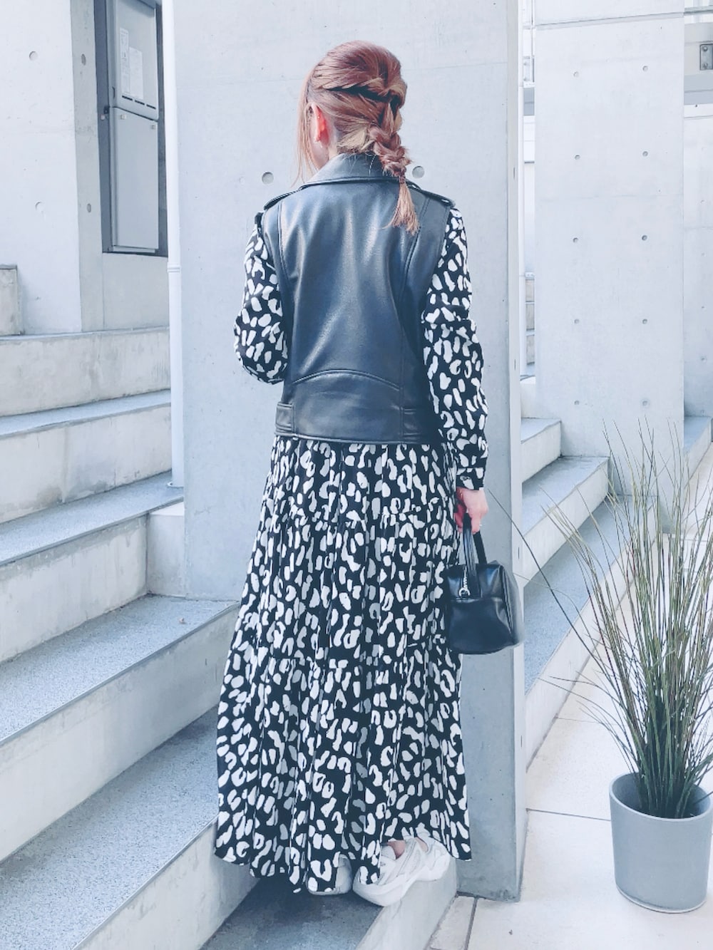 ブラック系のライダースジャケット、ブラック系のワンピース、ブラック系のハンドバッグを着用したレディースの春コーディネートの3枚目の写真