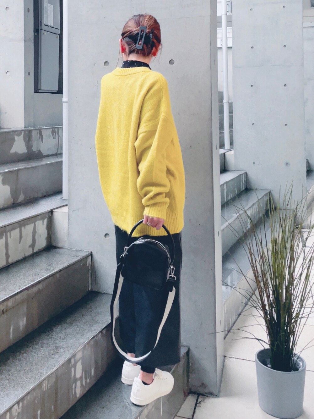 イエロー系のニット/セーター、ブラック系のハンドバッグ、ブラック系のスカートを着用したレディースの秋コーディネートの3枚目の写真