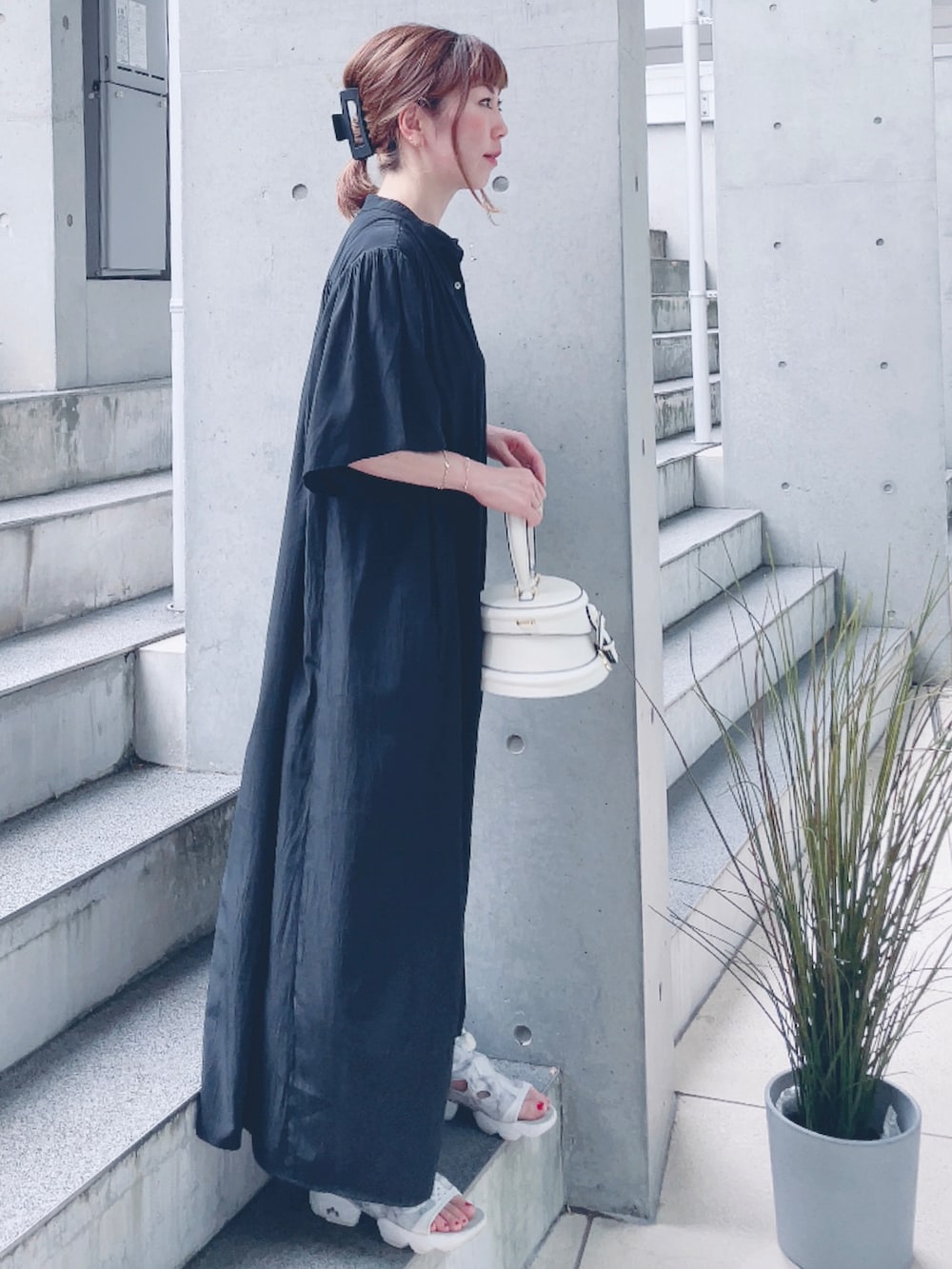 ブラック系のワンピース、ホワイト系のバッグ、ホワイト系のサンダルを着用したレディースの夏コーディネートの2枚目の写真