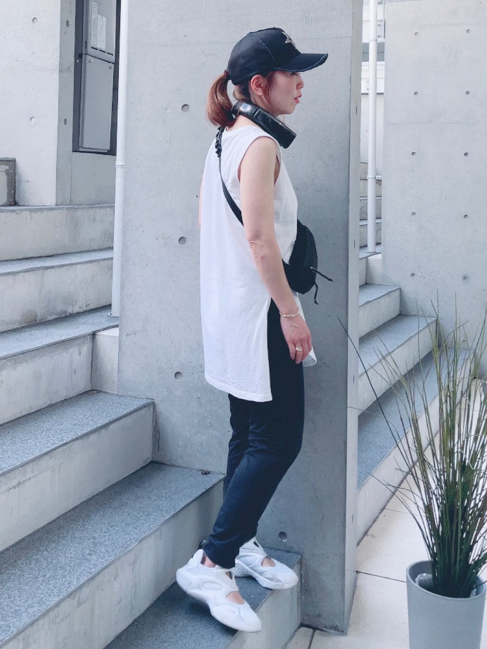 ホワイト系のタンクトップ、ホワイト系のスニーカー、ブラック系のキャップを着用したレディースの夏コーディネートの3枚目の写真