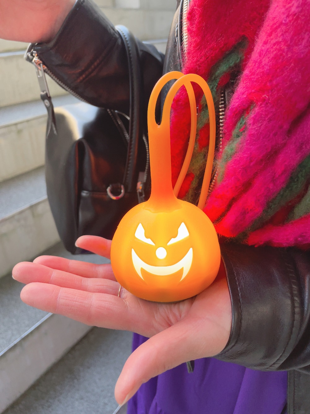 ブラック系のライダースジャケット、パープル系のワンピース、ブラック系のハンドバッグを着用したレディースの秋コーディネートの5枚目の写真