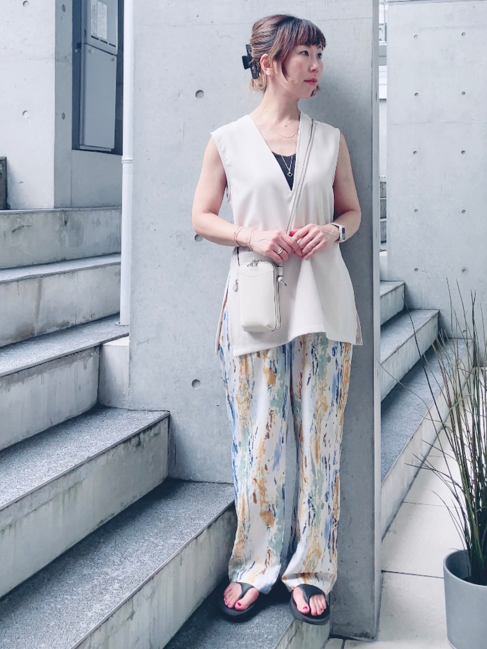 ベージュ系のベスト、ホワイト系のショルダーバッグ、ブラック系のサンダルを着用したレディースの夏コーディネートの2枚目の写真