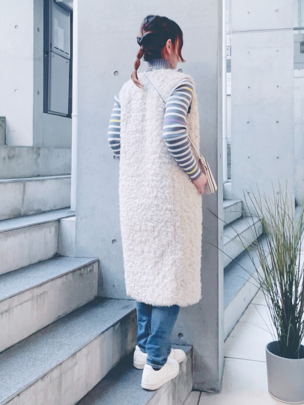 グレー系のニット/セーター、ブルー系のデニムパンツ、ホワイト系のショルダーバッグを着用したレディースの秋コーディネートの3枚目の写真