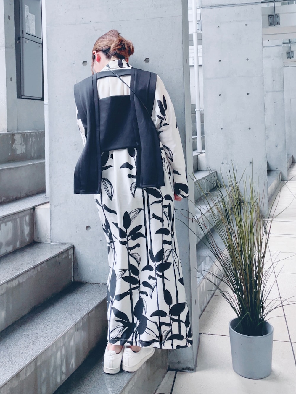 ブラック系のベスト、ホワイト系のシャツワンピース、ベージュ系のスニーカーを着用したレディースの春コーディネートの2枚目の写真