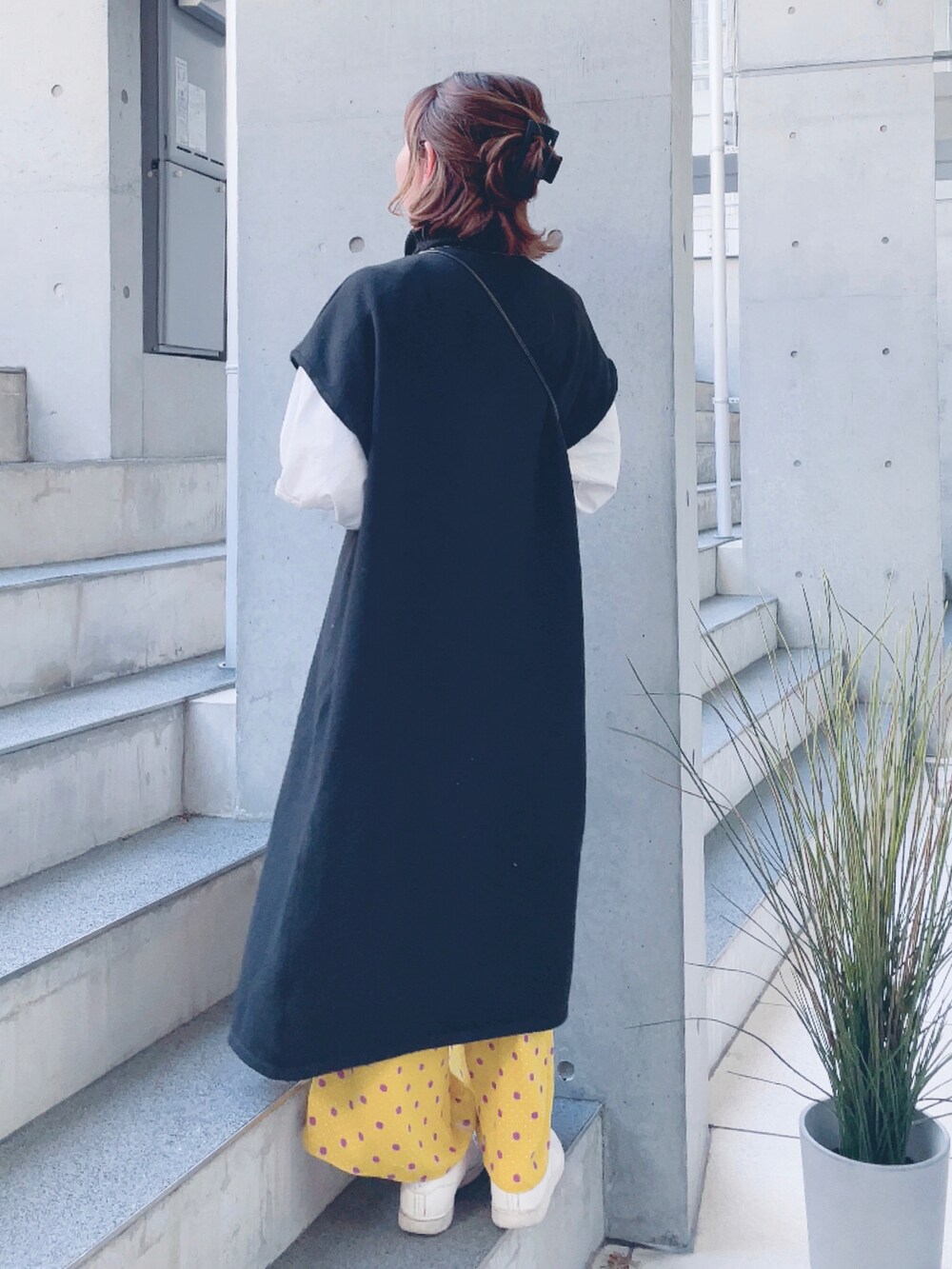 ブラック系のニット/セーター、ホワイト系のシャツ/ブラウス、ベージュ系のスニーカーを着用したレディースの春コーディネートの3枚目の写真