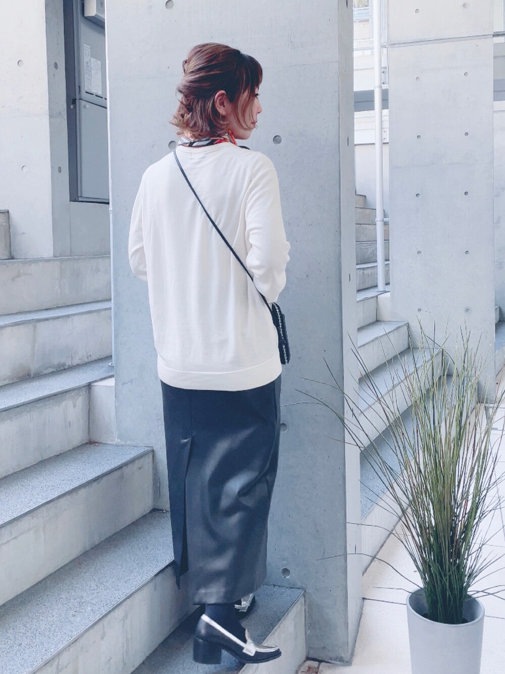 ブラック系のスカート、シルバー系のローファー、ブラック系のポーチを着用したレディースの春コーディネートの3枚目の写真