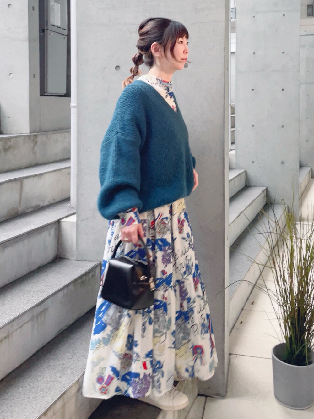 ホワイト系のワンピース、ブルー系のニット/セーター、ブラック系のハンドバッグを着用したレディースの冬コーディネートの2枚目の写真