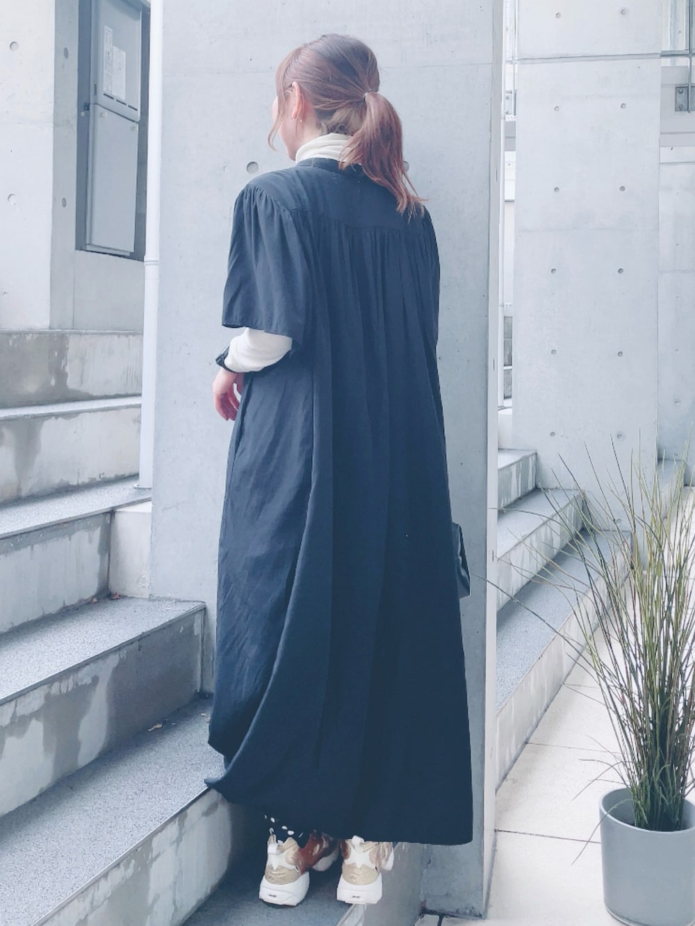 ブラック系のワンピース、ブラック系のハンドバッグ、ゴールド系のスニーカーを着用したレディースの春コーディネートの3枚目の写真