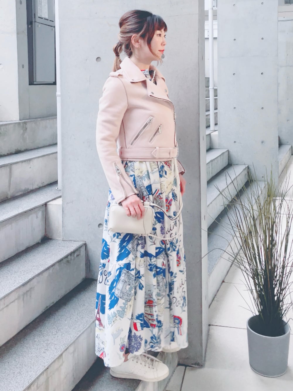 ピンク系のライダースジャケット、ホワイト系のワンピース、ベージュ系のスニーカーを着用したレディースの秋コーディネートの2枚目の写真