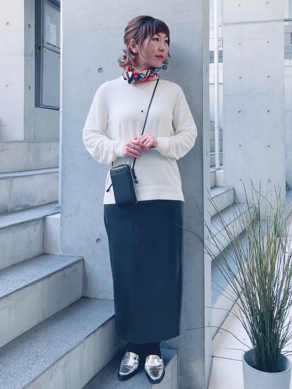 ブラック系のスカート、シルバー系のローファー、ブラック系のポーチを着用したレディースの春コーディネートの2枚目の写真