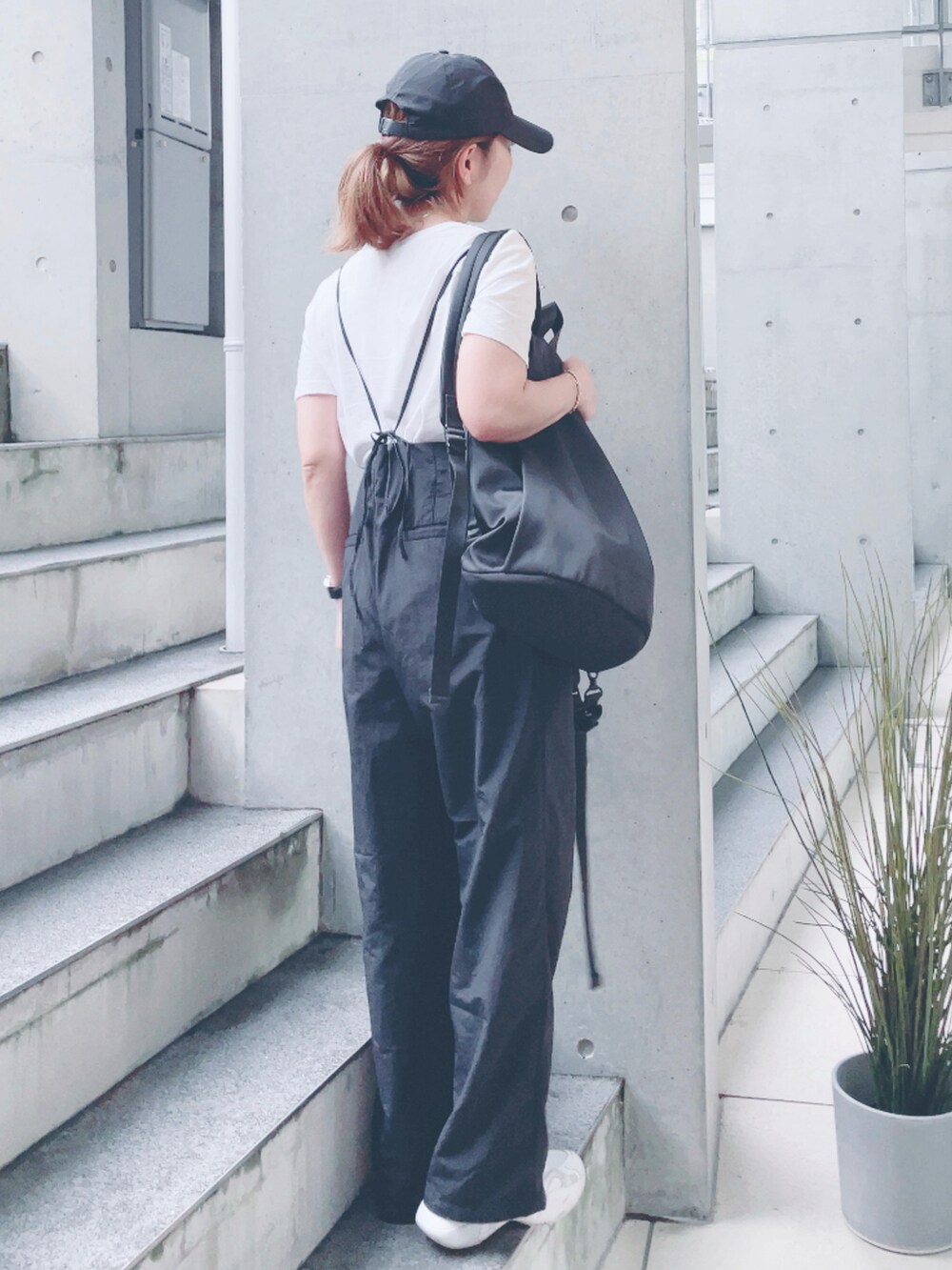 ブラック系のサロペット/オーバーオール、ブラック系のバックパック/リュック、ホワイト系のスニーカーを着用したレディースの秋コーディネートの2枚目の写真