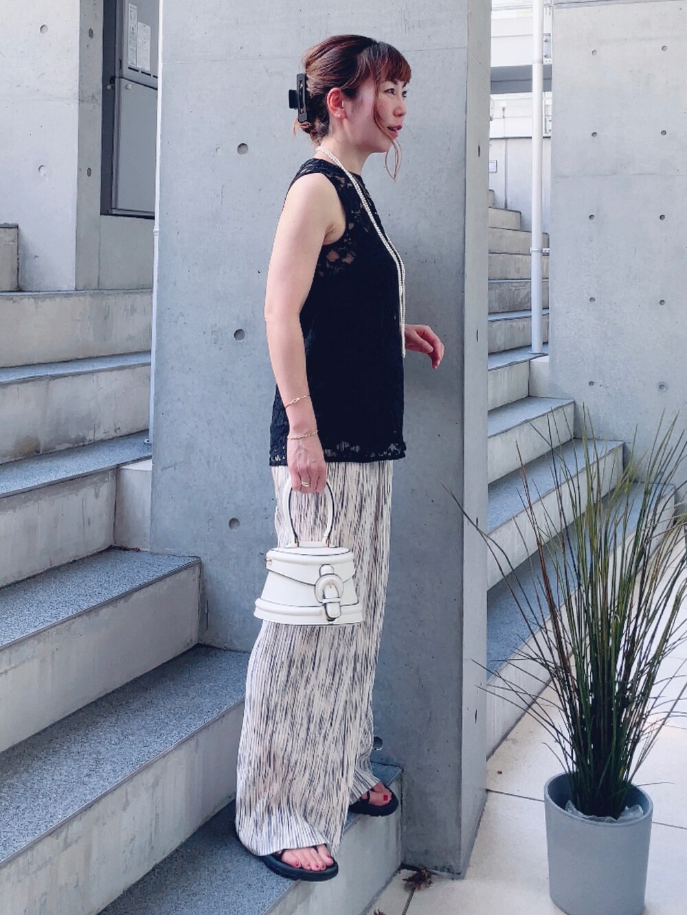 ベージュ系のその他パンツ、ホワイト系のバッグ、ブラック系のサンダルを着用したレディースの夏コーディネートの2枚目の写真