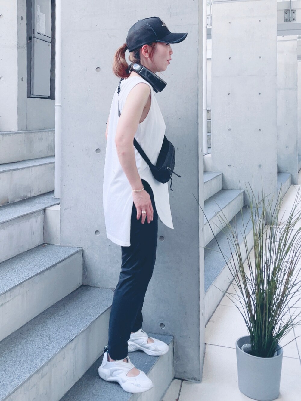 ホワイト系のタンクトップ、ホワイト系のスニーカー、ブラック系のキャップを着用したレディースの夏コーディネートの2枚目の写真