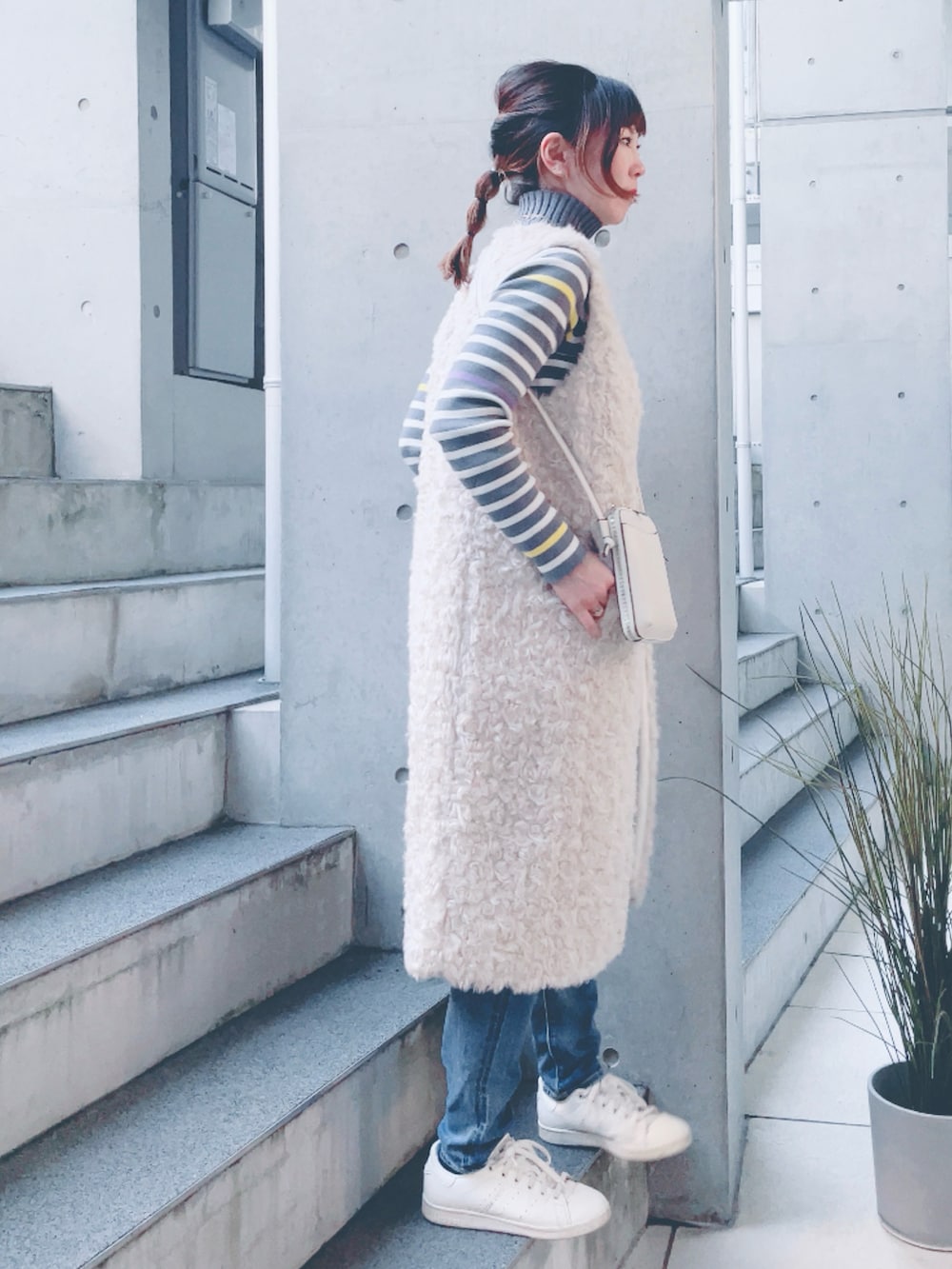 グレー系のニット/セーター、ブルー系のデニムパンツ、ホワイト系のショルダーバッグを着用したレディースの秋コーディネートの2枚目の写真