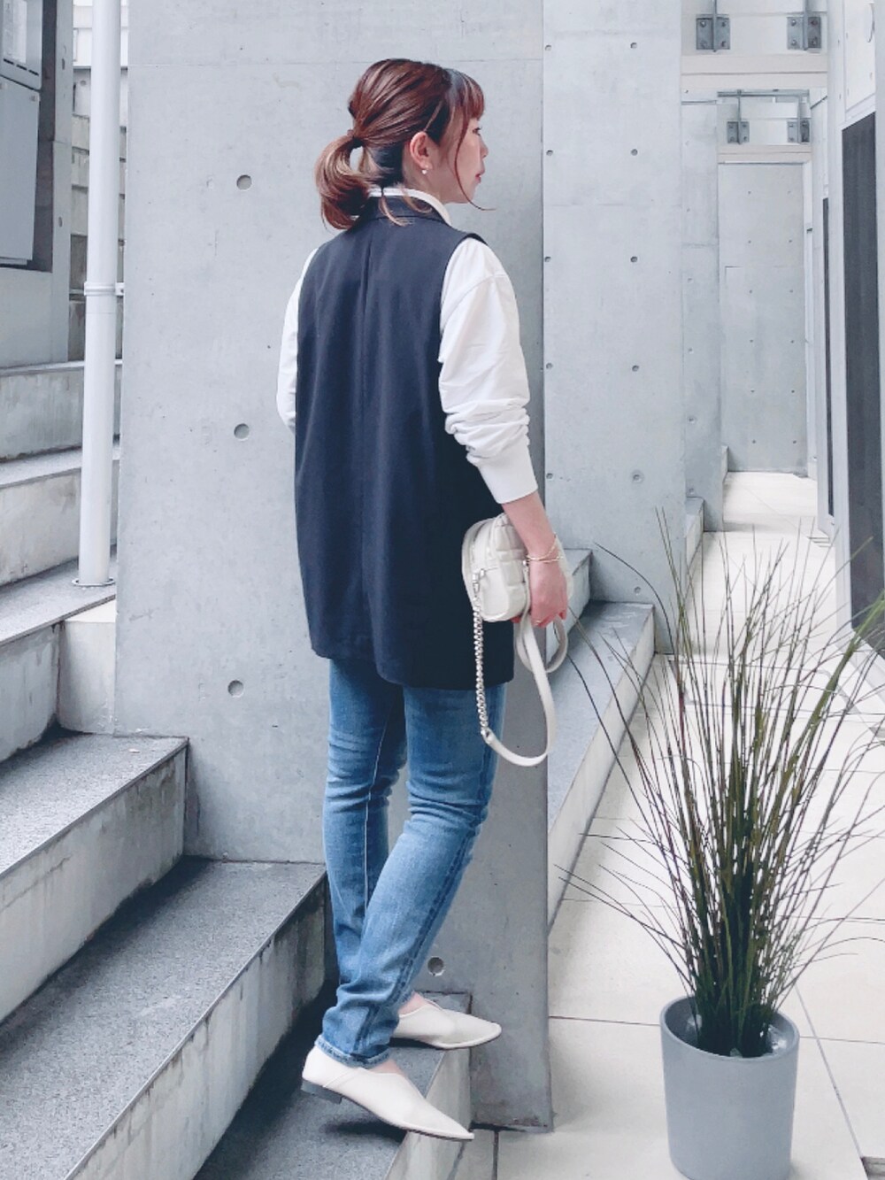 ブルー系のデニムパンツ、ベージュ系のパンプス、ゴールド系のショルダーバッグを着用したレディースの春コーディネートの3枚目の写真