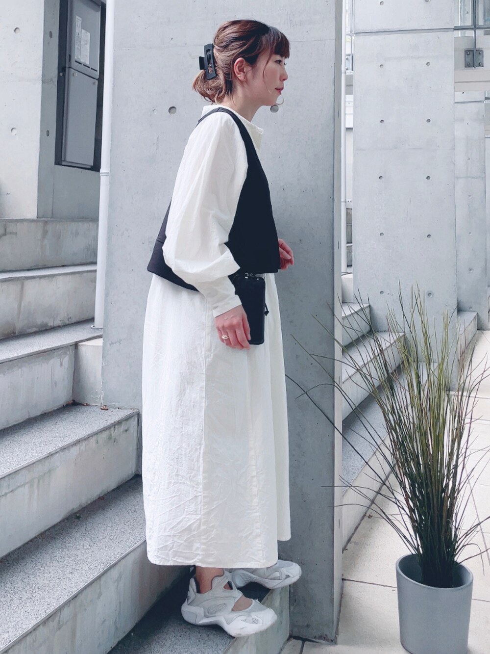 ホワイト系のワンピース、ホワイト系のスニーカー、ブラック系のポーチを着用したレディースの春コーディネートの2枚目の写真