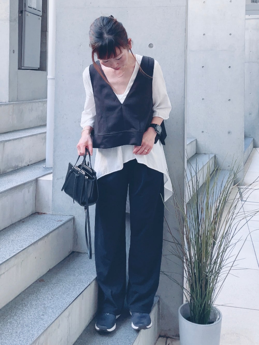 ブラック系のベスト、ホワイト系のシャツ/ブラウス、ブラック系のスニーカーを着用したレディースの秋コーディネートの2枚目の写真