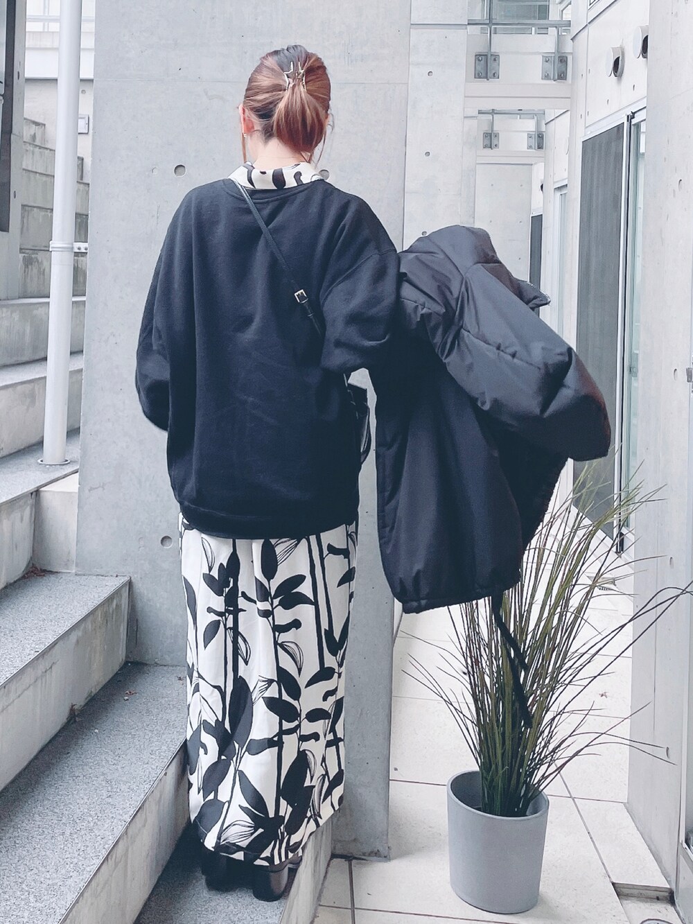 ブラック系のスウェット、ホワイト系のシャツワンピース、ブラック系のダウンジャケット/コートを着用したレディースの冬コーディネートの3枚目の写真