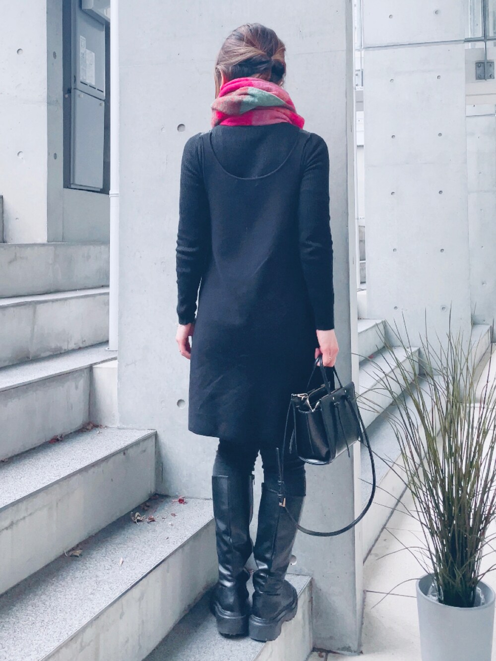 ブラック系のワンピース、ブラック系のブーツ、ピンク系のマフラーを着用したレディースの冬コーディネートの2枚目の写真