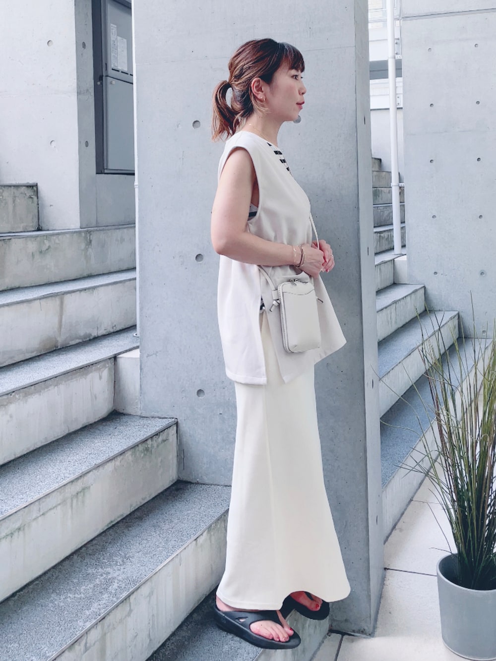 ホワイト系のスカート、ベージュ系のベスト、ホワイト系のタンクトップを着用したレディースの夏コーディネートの3枚目の写真