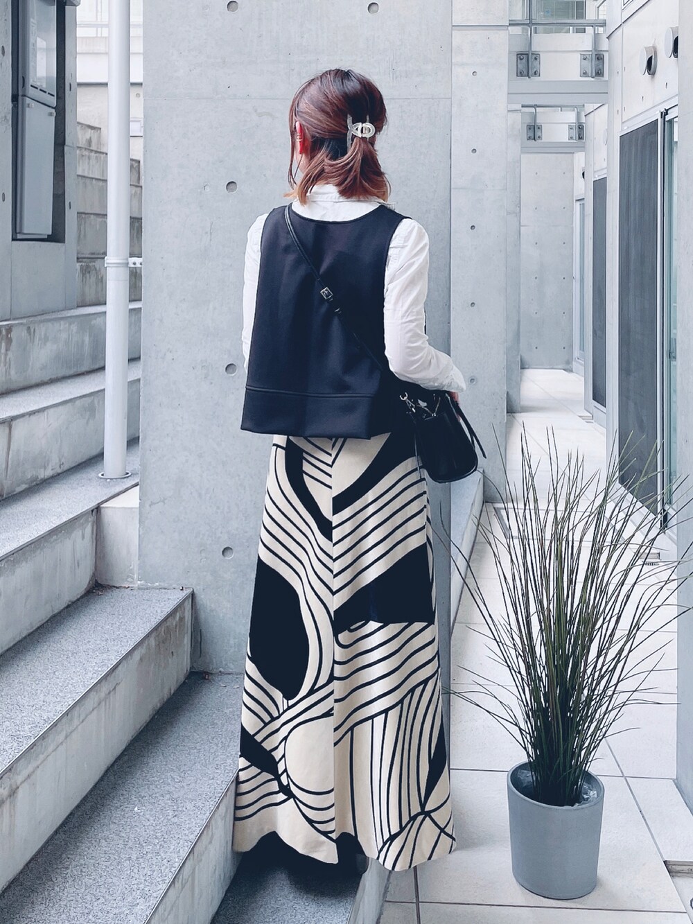 ブラック系のベスト、ホワイト系のシャツ/ブラウス、ベージュ系のスカートを着用したレディースの春コーディネートの4枚目の写真