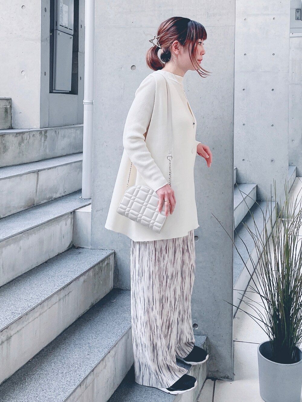 ホワイト系のベスト、ベージュ系のその他パンツ、ゴールド系のショルダーバッグを着用したレディースの秋コーディネートの2枚目の写真