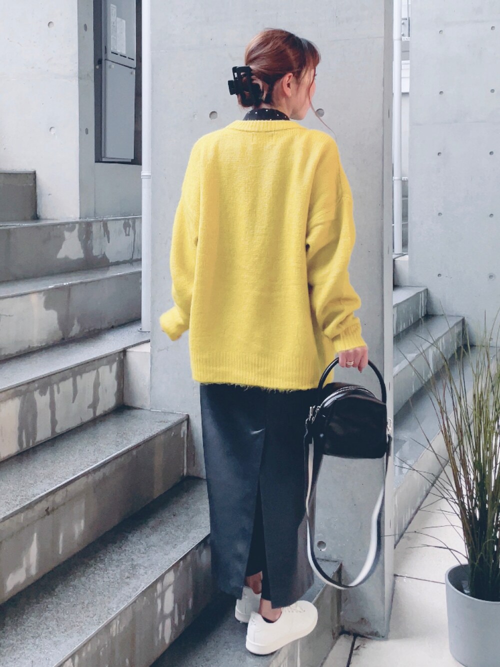 イエロー系のニット/セーター、ブラック系のハンドバッグ、ブラック系のスカートを着用したレディースの秋コーディネートの2枚目の写真