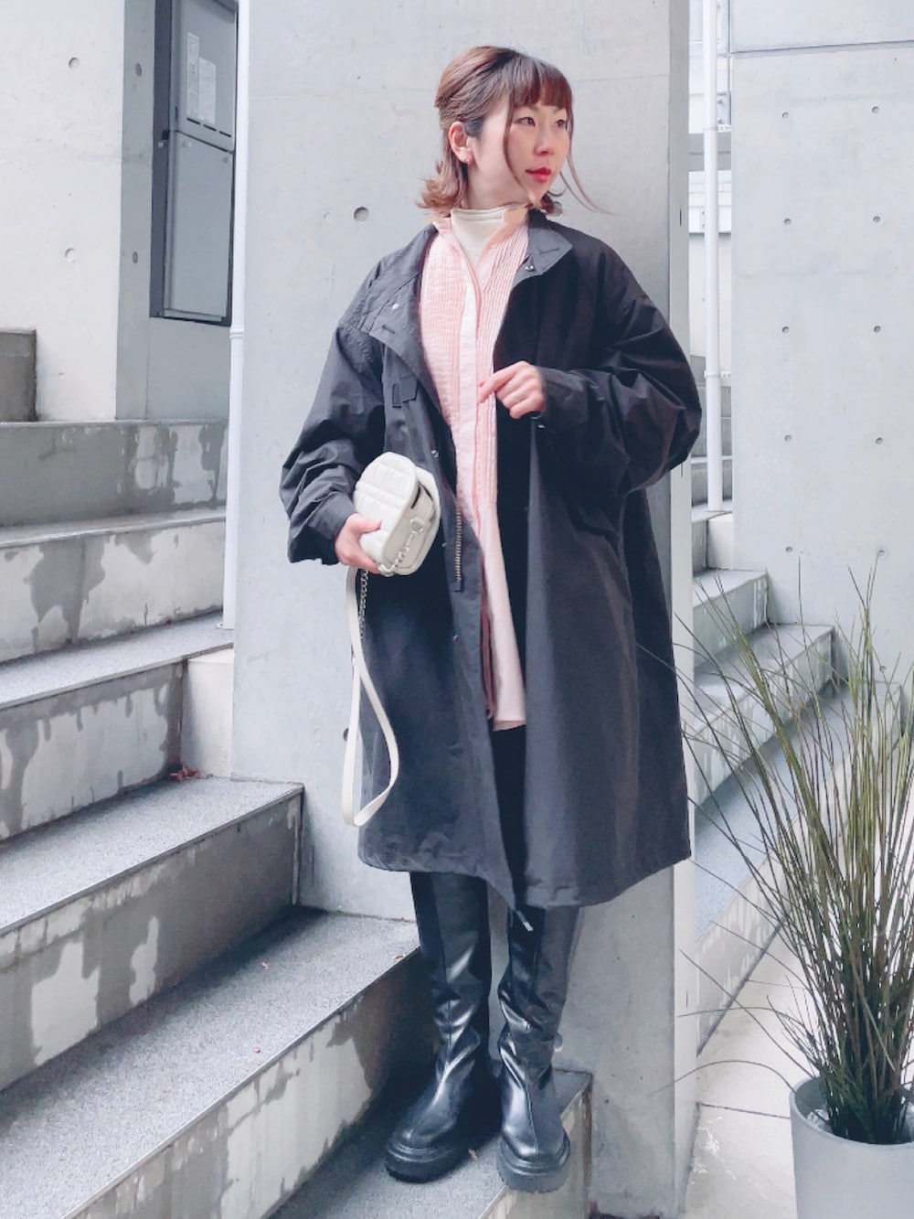 ブラック系のモッズコート、ブラック系のブーツ、ゴールド系のショルダーバッグを着用したレディースの冬コーディネートの2枚目の写真